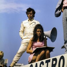 a woman sitting on top of a box next to a man holding a megaphone