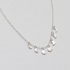 "The Moon Phases Necklace is a chic, stylish piece that can be worn with almost anything! The 7 various moon pendants dangle lightly from a delicate 16\" cable chain that features a 2\" extender (max necklace length is 18\"). - Available in 14K Gold Plated Brass or Rhodium Plated Sterling Silver - Handmade - FREE SHIPPING within the United States" Elegant Moon-shaped Charm Necklaces, Minimalist Silver Necklaces With Dangling Charms, Elegant Moon Shaped Charms Necklace, Minimalist Silver Necklace With Dangling Charms, Elegant Moon Shaped Necklace With Charms, Elegant Moon-shaped Necklace With Charms, Dainty Half Moon Charm Necklace With Moon Phase, Dainty Half Moon Phase Charm Necklace, Minimalist Moon Shape Charm Necklace With Clavicle Chain