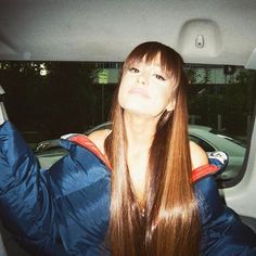 a woman sitting in the back seat of a car with her hair flying up and down