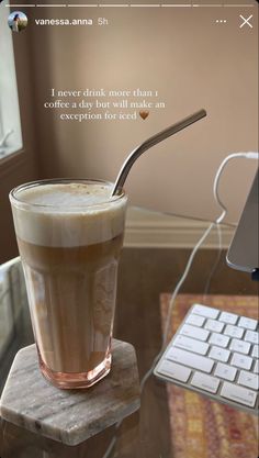 a drink with a straw in it sitting on top of a table next to a keyboard