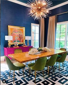 a dining room with blue walls and colorful furniture in the center, along with a chandelier that hangs from the ceiling