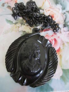 Vintage circa 1930 black celluloid cameo necklace. This vintage 2.5'' black gothic necklace features a large celluloid cameo on a 22'' celluloid link chain. The chain has a hook closure that closes in the front. This estate find is large and wonderful. It wears with a bold style. The cameo has beautiful features and it is beautifully framed on it's carved backdrop. Lovely vintage condition. Black Cameo Medallion Jewelry, Black Cameo Jewelry For Collectors, Collectible Black Cameo Jewelry, Vintage Black Cameo Necklace, Vintage Black Cameo Jewelry, Black Cameo Necklace In Vintage Style, Vintage Black Carved Jewelry, Vintage Black Medallion Necklace, Black Cameo Medallion Necklace