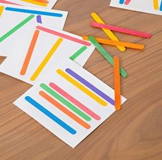 several pieces of paper with colored sticks sticking out of them sitting on a table next to each other