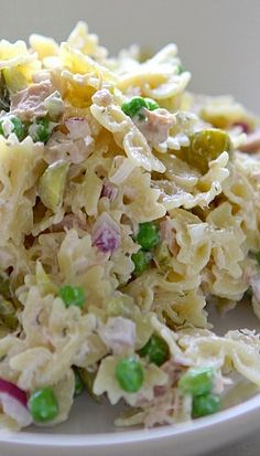 a close up view of a pasta salad with peas and other toppings on a white plate