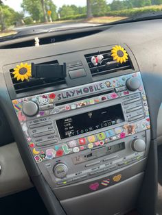 the dashboard of a car with sunflowers and stickers on it's dash board