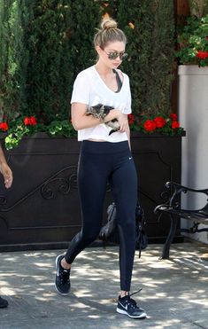 a woman in black leggings and white shirt walking with a small cat on her shoulder