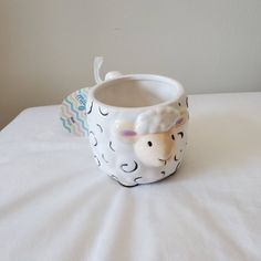 a ceramic sheep mug sitting on top of a bed