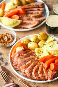 a plate with meat, potatoes and carrots on it next to a glass of beer