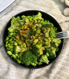 a black bowl filled with broccoli and peas