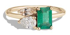 an emerald and diamond three stone ring with two diamonds on each side, set in yellow gold