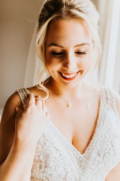 a woman in a wedding dress smiles as she adjusts her bracelet