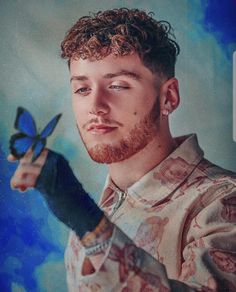 a man with curly hair holding a pair of scissors in one hand and looking at the camera