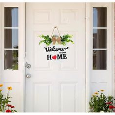 a welcome home sign hanging on a door with flowers in the front and behind it