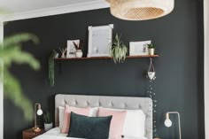 a white bed topped with pillows next to a shelf filled with potted plants and greenery