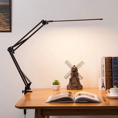 an open book sitting on top of a wooden desk next to a lamp and books