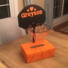 an orange basketball hoop with the word greyson on it sitting on top of a wooden table