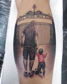 a man with a tattoo on his leg holding the hand of a little boy who is standing in front of a gate