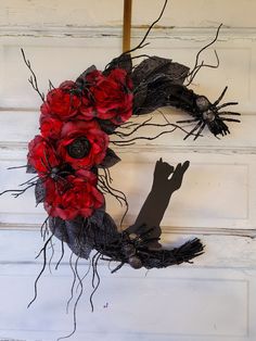 a wreath with red flowers is hanging on the front door and black cat silhouette next to it