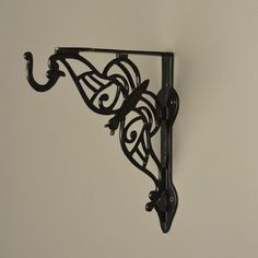 an ornate black metal shelf bracket on a white wall