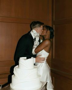 a bride and groom kissing in front of a wedding cake