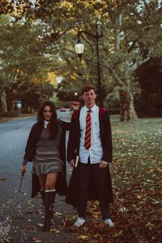 a man and woman dressed up in harry potter costumes walking down the street with their arms around each other