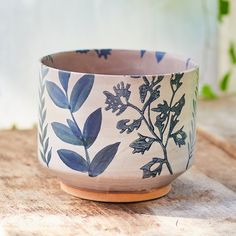 a blue and white bowl sitting on top of a wooden table next to a plant