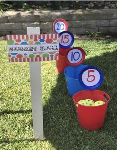 buckets filled with apples are sitting in the grass next to a sign that says bucket ball