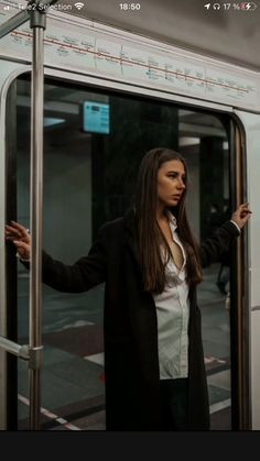 a woman is standing on the door of a train and holding her hand out to another person