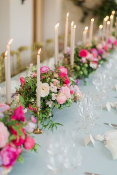 a long table with candles and flowers on it is set up for a formal dinner