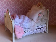 a doll's bed with pink and white decor