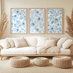 a living room with three blue and white paintings on the wall next to a wicker ottoman