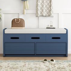 a blue bench with two drawers and a handbag on the top, in front of a white wall