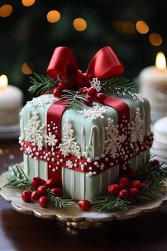 a christmas cake decorated with red bows and snowflakes sits on a table in front of candles