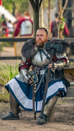 a man dressed in armor sitting on a bench