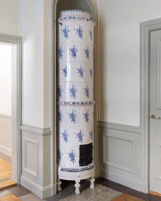 a tall white and blue vase sitting in the corner of a room next to a doorway