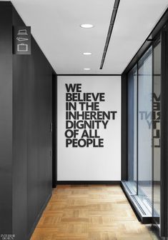 an empty hallway with black and white wall decals on the walls that read we believe in the different identity of all people