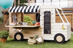 an ice cream truck is set up in the grass with some balloons and other decorations