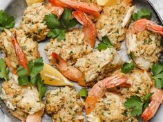 a plate with shrimp, lemons and parsley garnished with herbs on it