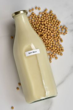 a glass bottle filled with soy seeds next to a pile of chickpeas