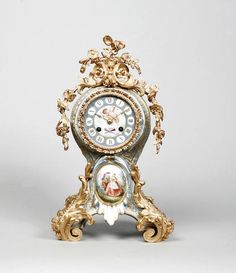 an ornate gold and white clock with cherubs on the sides, against a gray background