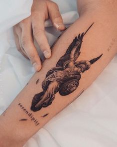 a woman's arm with a tattoo on it that has an image of a winged angel