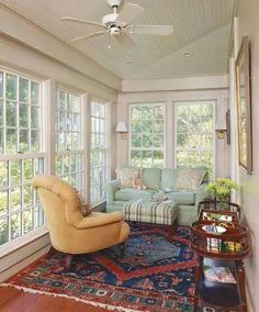 a living room filled with furniture and windows next to a rug on top of a hard wood floor