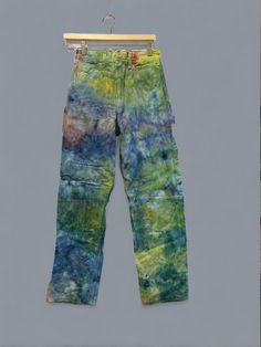 a pair of tie - dyed jeans hanging on a clothes hanger