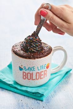 someone is dipping chocolate into a mug with sprinkles on the top and bottom