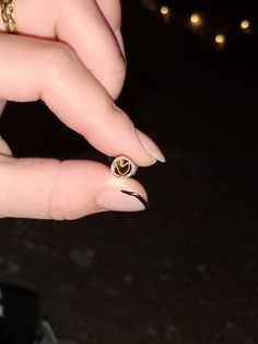 a woman's hand holding a gold ring with two hearts on the middle finger