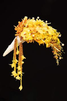 yellow flowers are hanging down from the side of a headdress with beads on it