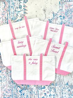 five pink and white bags with sayings on them sitting on a blue patterned rug