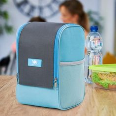 a lunch bag sitting on top of a wooden table next to a container with a sandwich in it