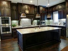 a kitchen with dark wood cabinets and marble counter tops