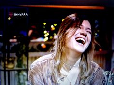 a woman laughing while standing in front of a tv screen with the words nirvana on it